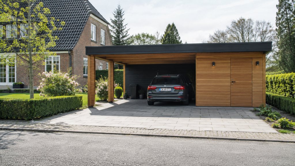 Åben carport med fladt tag båret af kraftige træstolper, opført ved siden af et gult murstenshus med en bil parkeret under